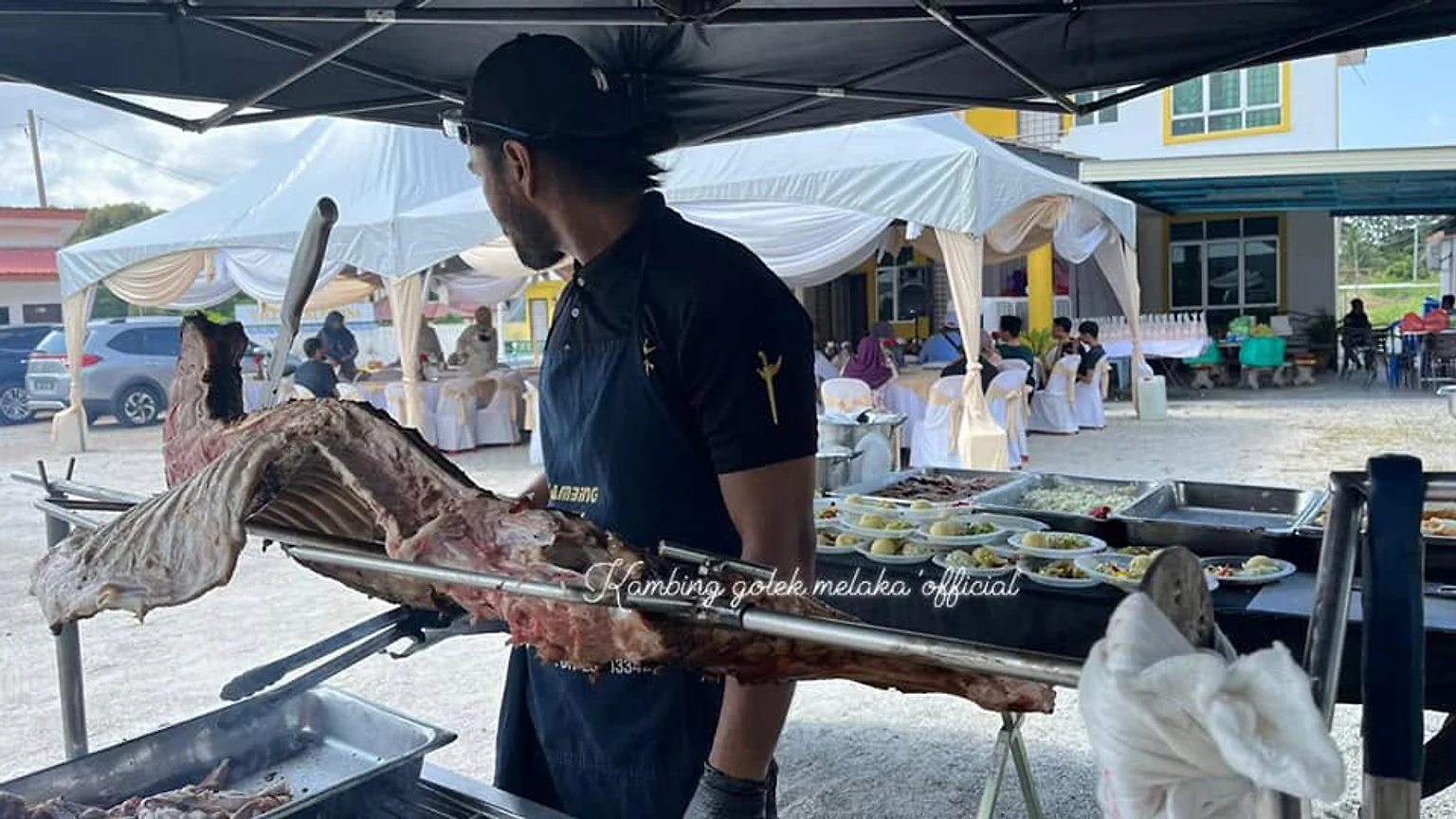 Krew mengangkat kambing golek untuk dihidangkan